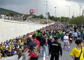 Large Crowd Walking Along a Closed Road, Many in Green/yellow Shirts, with Onlookers Atop a Concrete Barrier. - Entre Regios