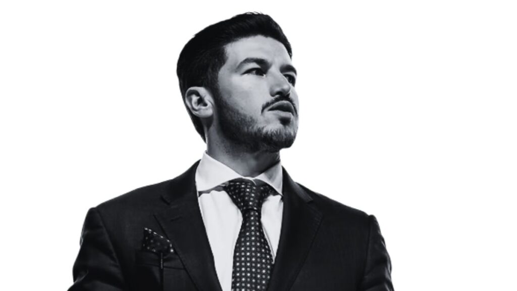 Man in a Dark Suit with a Patterned Tie and Pocket Square Gazing Upward Against a White Background, Portrait-style Image. - Entre Regios