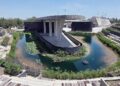 Modern Circular Pond with a Concrete Pavilion on a Curved Wall, Surrounded by Stepped Seating and Greenery in a Plaza. a Small Fountain Floats on the Water Surface. - Entre Regios